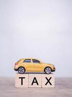 Toy car and Wooden blocks with the word TAX . The concept for paying TAX for car in future photo