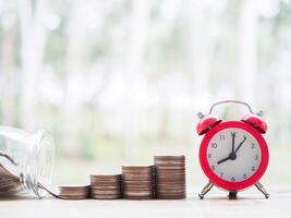 Red alarm clock on stack of coins. The concept of saving money for manage time to success business. photo