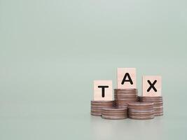 Wooden blocks with the word TAX on stack of coins. The concept about saving money and manage time to paying tax photo