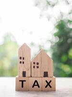 Miniature house and Wooden blocks with the word TAX. The concept of payment tax for house, Property investment, House mortgage, Real estate photo