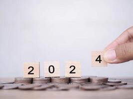 Wooden block with number 2024 on stack of coins. The concept of saving money for business achievement goal, Financial, Investment and Business growing in new year 2024. photo