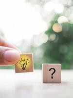 Close up hand arranging wooden block with light bulb and wooden block with question mark for leadership, creative, idea, innovation concept. photo
