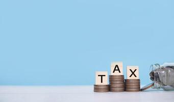 Wooden blocks with the word TAX on stack of coins. The concept of saving money for payment tax in future photo