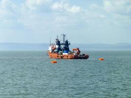 un pequeño Servicio Embarcacion en un carga industrial puerto. un Embarcacion en el mar foto