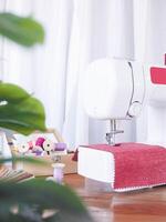 Close up sewing machine working with red fabric, sewing accessories on the table, stitch new clothing. photo