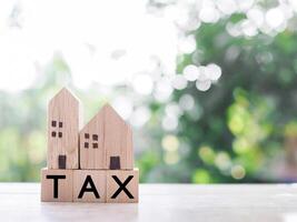 Miniature house and Wooden blocks with the word TAX. The concept of payment tax for house, Property investment, House mortgage, Real estate photo