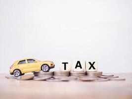 Toy car and wooden blocks with the word TAX on stack of coins. The concept of saving and manage money to success transportation, Paying tax and car loan photo