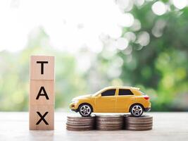 Wooden blocks with the word TAX and Toy car on stack of coins. The concept of saving and manage money to success transportation, Paying tax and car loan photo