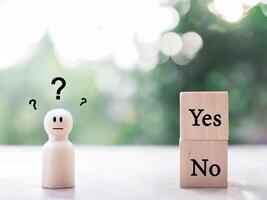 Wooden human figure with question marks. The concept of choice Yes or No. Choice hesitate, making decision photo