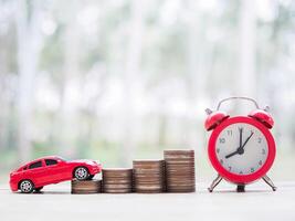 juguete auto, apilar de monedas y rojo alarma reloj. el concepto de ahorro dinero y gestionar a éxito transporte negocio foto