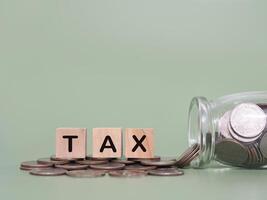 Wooden blocks with the word TAX and stack of coins. The concept about saving money and manage time to paying tax photo