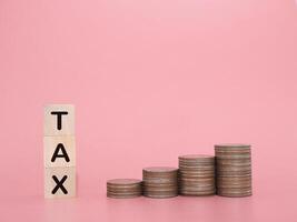 Wooden blocks with the word TAX and stack of coins. The concept about saving money and manage time to paying tax photo