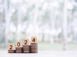 Wooden block with number 2024 on stack of coins. The concept of saving money for business achievement goal, Financial, Investment and Business growing in new year 2024. photo