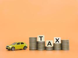 Toy car and wooden blocks with the word TAX on stack of coins. The concept of saving and manage money to success transportation, Paying tax and car loan photo