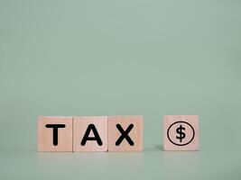 Wooden blocks with the word TAX and stack of coins. The concept about saving money and manage time to paying tax photo