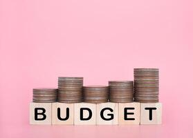 Wooden blocks with the word BUDGET and stack of coins. The concept about budget planning and allocation photo