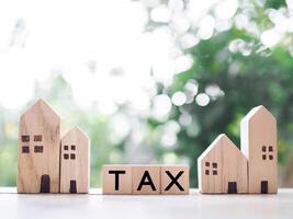 Miniature house and Wooden blocks with the word TAX. The concept of payment tax for house, Property investment, House mortgage, Real estate photo