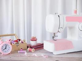 cerca arriba de coser máquina trabajando con rosado tela, de coser accesorios en el mesa, puntada nuevo ropa. foto