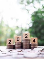 Wooden block with number 2024 on stack of coins. The concept of saving money for business achievement goal, Financial, Investment and Business growing in new year 2024. photo