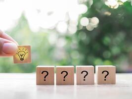 Close up hand arranging wooden block with light bulb and wooden block with question mark for leadership, creative, idea, innovation concept. photo