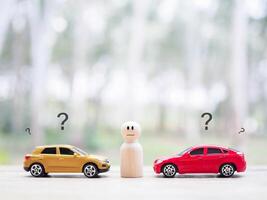 Wooden human figure and Toy car with question mark icons.The concept of choosing suitable car for the future. photo