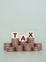 Wooden blocks with the word TAX and stack of coins. The concept about saving money and manage time to paying tax photo