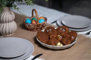 Pascua de Resurrección mesa ajuste con vacío gris platos, multi de colores huevos en mimbre cesta y florero con verde planta en en Manteles foto