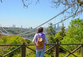 un joven mujer turista con un mochila disfruta un panorámico ver de el fatih sultán mehmet puente. espalda ver el foto estaba tomado desde otagtepe