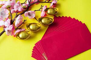 Top view of Chinese New Year red packet, cherry blossom and golden ingots decoration. Copy space photo