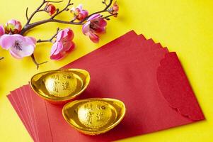 Top view of Chinese New Year red packet, cherry blossom and golden ingots decoration photo