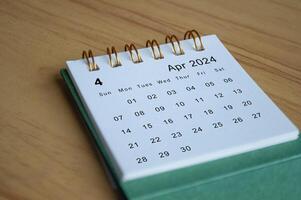 Close up side view of April 2024 calendar on wooden desk. Calendar concept photo