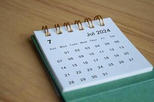Close up side view of July 2024 calendar on wooden desk. Calendar concept photo