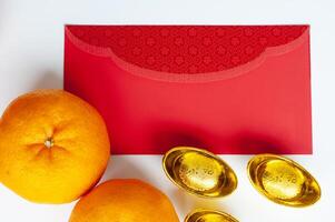 Top view of red packet with golden ingot and Mandarin oranges. Customizable space for text photo