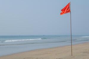 rojo bandera en playa en mar o Oceano como un símbolo de peligro. el mar estado es considerado peligroso y nadando es prohibido. foto