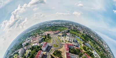 Aerial view from high altitude tiny planet in sky with clouds overlooking old town, urban development, buildings and crossroads. Transformation of spherical 360 panorama in abstract aerial view. photo