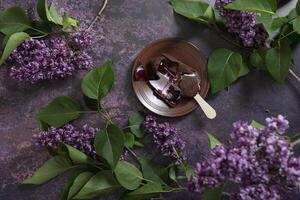 melted raspberry ice cream in chocolate on a wooden stick on a dark table photo