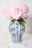 rosado lujoso peonías en un antiguo chino florero con azul ornamento, primavera foto