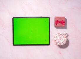 tablet with green screen gift in red box and cup of cappuccino with marshmallow photo