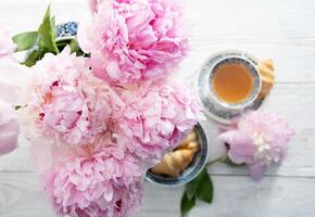 delicado primavera todavía vida con croissants y un ramo de flores de rosado peonías foto