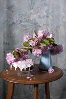 Pascua de Resurrección pastel y pintado huevos y un ramo de flores de rosado sakura flores en un mesa foto