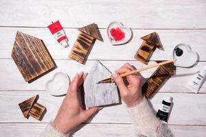 woman drawing heart on wooden house, crafting, step by step instructions how to make decor for valentines, mothers day photo