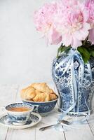 delicate spring still life with croissants and a bouquet of pink peonies photo