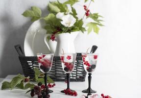 transparent gin and tonic with ice and fresh red currants and blackberries photo