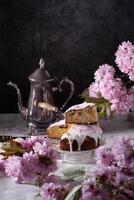 Easter cake and painted eggs and a bouquet of pink sakura flowers on a table photo