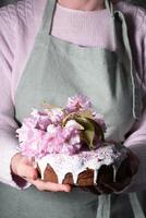 a woman decorates a homemade Easter cake with pink sakura flowers,spring blossom photo