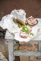 Lard with black bread, pickled cucumber for a snack and a glass of vodka , Still life on a peeling old stool photo