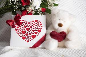 Valentines day gift, teddy bear with a heart, a box of pralines and a bouquet photo