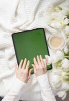 verde pantalla tableta, joven mujer mirando para de la madre día regalo en línea, tulipanes foto