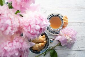 delicado primavera todavía vida con croissants y un ramo de flores de rosado peonías foto