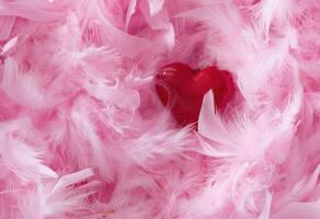 The red toy heart lies on the surface with pink fluffy feathers natural delicate photo